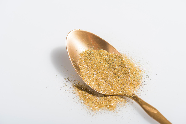 golden spoon and bright glitter on white - Valokuva, kuva