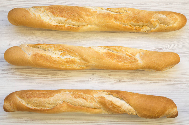 Baguetes francesas frescas em fundo de madeira branca, vista superior
.  - Foto, Imagem