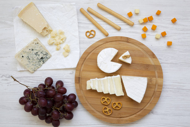 Tasting cheese with grapes, bread sticks, walnuts and pretzels on wooden background, top view. Food for romantic. Flat lay. From above. - Photo, Image