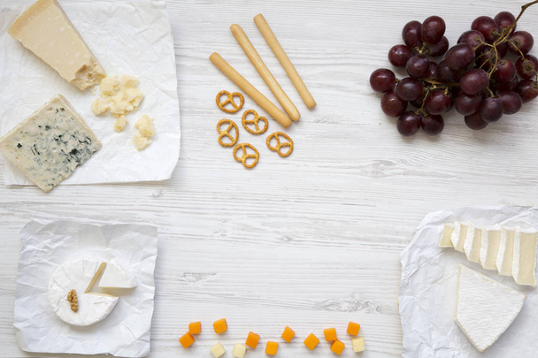 Dégustation de fromage avec raisins, bâtonnets de pain, noix et bretzels sur fond bois, vue sur le dessus. Nourriture romantique. Pose plate. D'en haut. Espace de copie
. - Photo, image