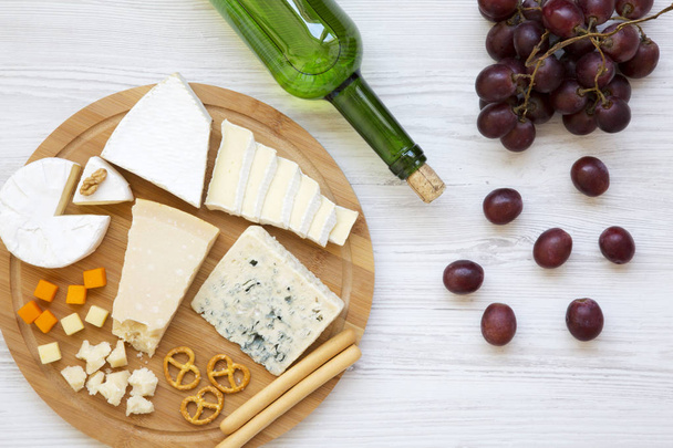 Tasting delicious cheese with wine, grapes, walnuts and pretzels on wooden background, top view. Food for romantic. From above. Flat lay.  - Photo, Image
