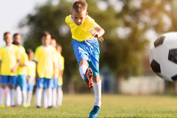 Chłopiec kopie piłka nożna na boisko sportowe w piłkę nożną - Zdjęcie, obraz