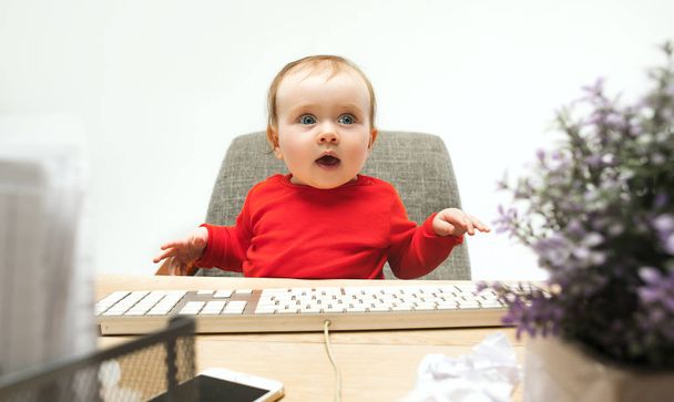 Happy child baby girl toddler sitting with keyboard of computer isolated on a white background - Valokuva, kuva