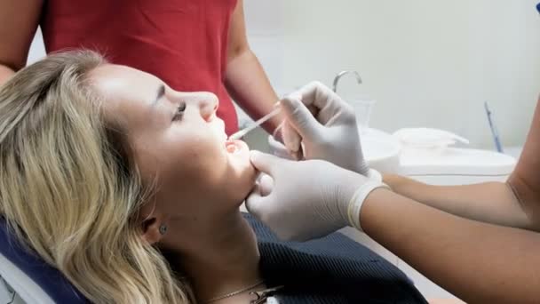 Closeup 4k πλάνα του οδοντιάτρου αφαίρεση κραγιόν με μπατονέτα από ασθενείς των δοντιών - Πλάνα, βίντεο