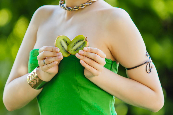 Cerrar las manos de una mujer sosteniendo dos mitades de kiwi en forma de corazón
 - Foto, imagen