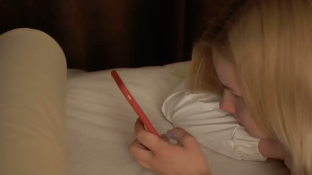 Young blonde lies on couch and uses her phone - Séquence, vidéo