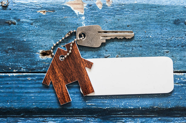 Ház kulcsát egy ház alakú kulcstartó pihent a fa háttér, real estate koncepció - Fotó, kép