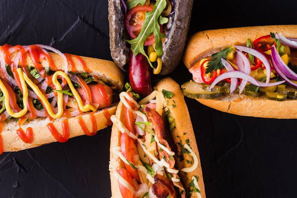 vier Hot Dogs auf dunklem Hintergrund (Ansicht von oben schließen) - Foto, Bild