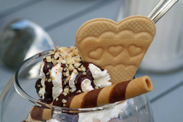 Közelkép a krém mogyoró sprinkles és waffle, szív alakú, csokoládé öntettel - Fotó, kép