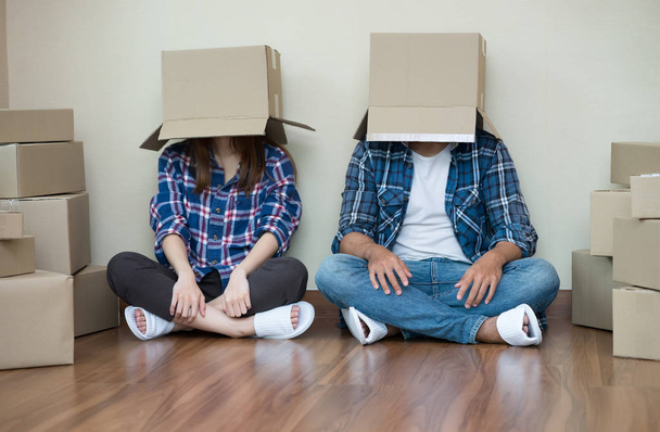 Couple drôle se déplacer avec des boîtes en carton vides sur leur tête assis sur le sol après à la nouvelle maison
 - Photo, image