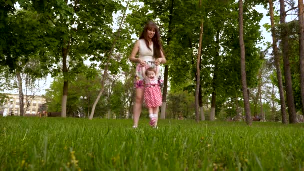 Maminka se třese rukou ve vzduchu s šťastný smích dcery. Rodič s dítětem hraje na zelené trávě v letním parku. Štěstí mateřství. - Záběry, video