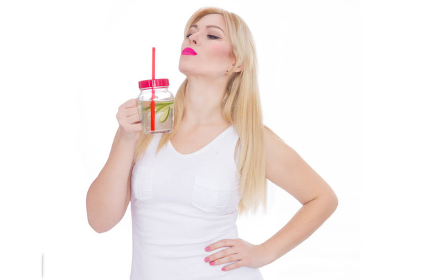 A friendly blond woman holds a glass of water and lime in her hands. A girl is drinking lemonade. Concept - healthy food, thirst quenching in summer - Foto, Bild