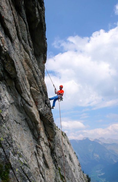 male rock climber abseiling off a steep rock climbing route in the Swiss Alps after a hard climb - Fotoğraf, Görsel