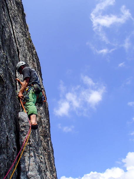 escalador de roca vestido de colores brillantes en una empinada ruta de escalada de granito en los Alpes
 - Foto, Imagen