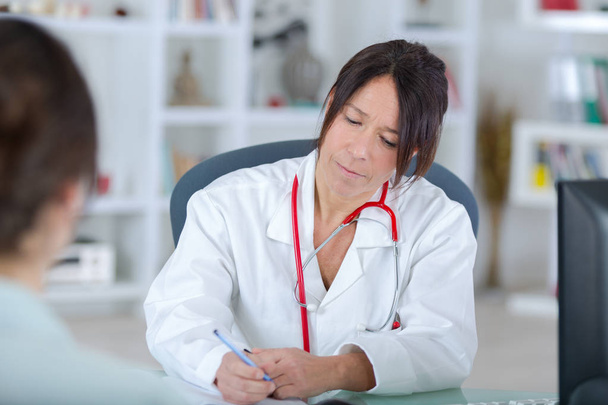 female doctor listening to her patientin office - Foto, afbeelding