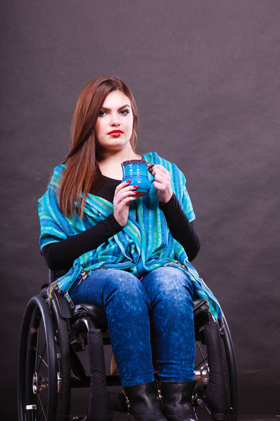 Dronk beverage disability happiness joy concept. Smiling disabled lady. Young crippled girl sitting on wheelchair holding blue cup. - Zdjęcie, obraz