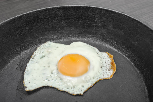 frigideira com ovos fritos em um fundo escuro de madeira
 - Foto, Imagem