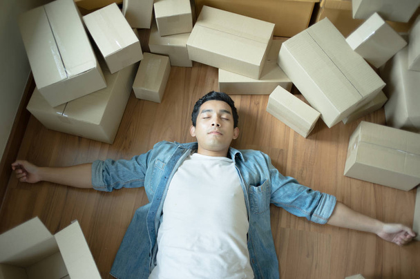 Beau homme fatigué de l'emballage couché sur le sol avec des boîtes et dormir
 - Photo, image