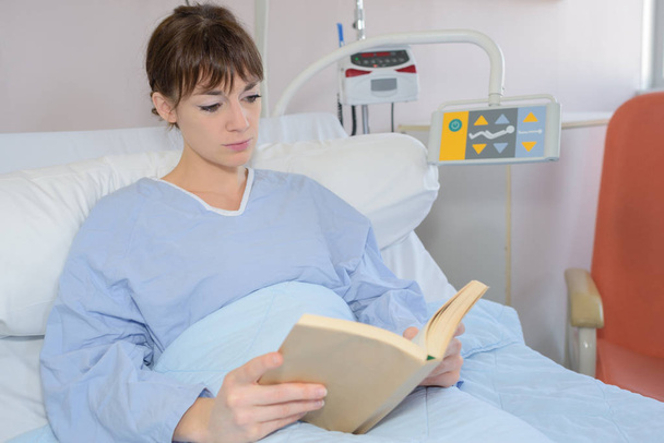 Patiente qui lit dans un lit d'hôpital
 - Photo, image