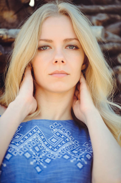 mujer joven con el pelo largo rubia hermosa recta está vestida con un vestido azul sobre un fondo de madera
. - Foto, Imagen