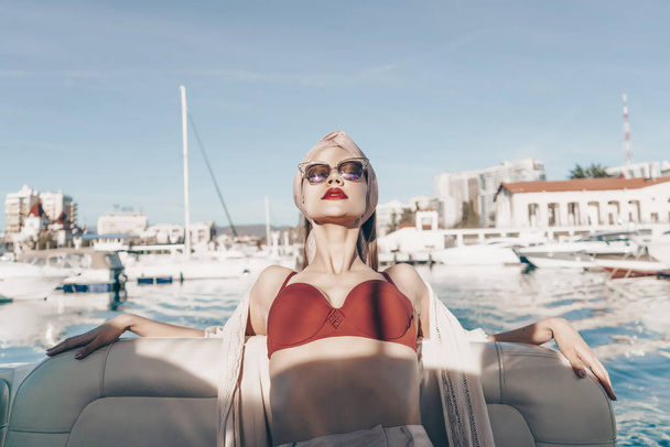 an elegant rich woman in sunglasses relaxes on her yacht, sails to the islands on vacation - Fotó, kép
