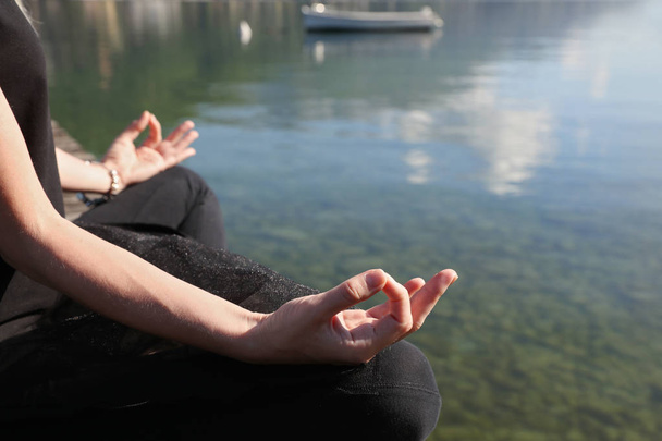 Woman meditating near mountain lake close up - Photo, Image