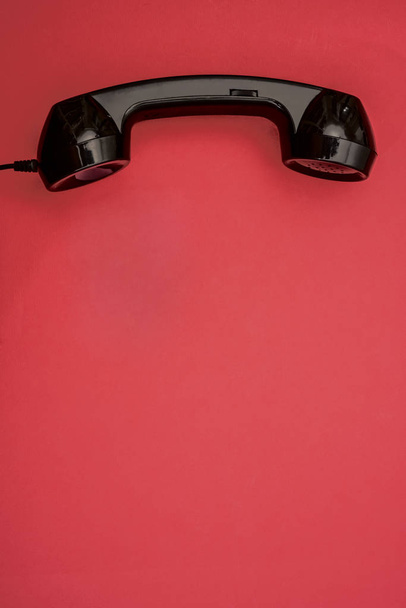 Telephone. black handset on red paper background.  - Foto, imagen