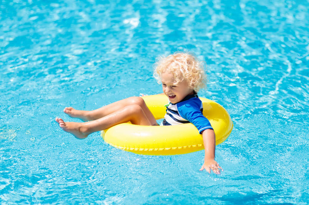 Child with goggles in swimming pool. Little boy learning to swim and dive in outdoor pool of tropical resort. Swimming with kids. Healthy sport activity for children. Sun protection. Water fun. - Foto, Bild