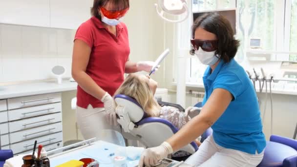 Imágenes de 4k del dentista y asistente tratando los dientes de los pacientes con fotopolímero de curado
 - Metraje, vídeo