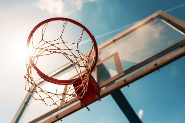 Sunlight shining through basketball hoop with net - Фото, зображення