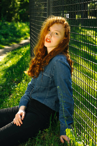 Ihana punapää nuori nainen sininen denim paita poseeraa auringonsäteet puistossa
 - Valokuva, kuva