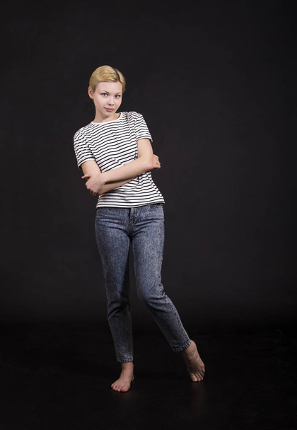 Young woman in striped t-shirt posing emotionally on dark background. Isolated image, Studio shot on dark background. - Фото, изображение
