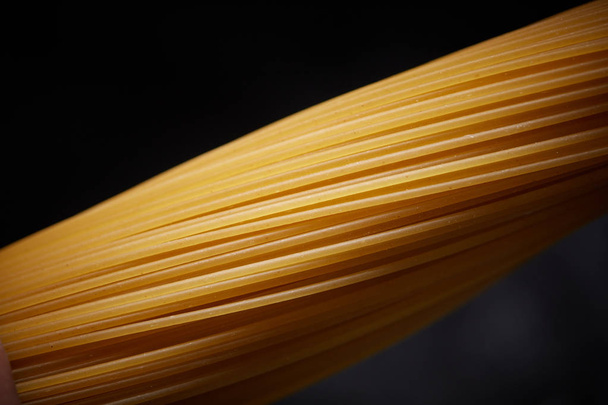 Macro photo of yellow long Italian spaghetti on a black background - Valokuva, kuva
