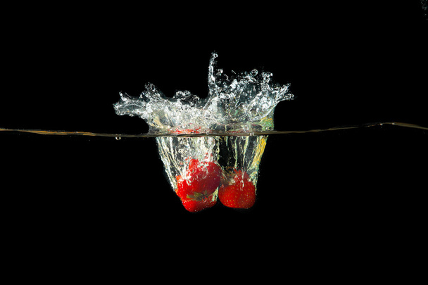 Fresh strawberry dropped into water with splash - Foto, Bild