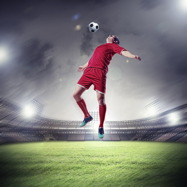 Football player in red shirt striking the ball at the stadium - Foto, Imagen