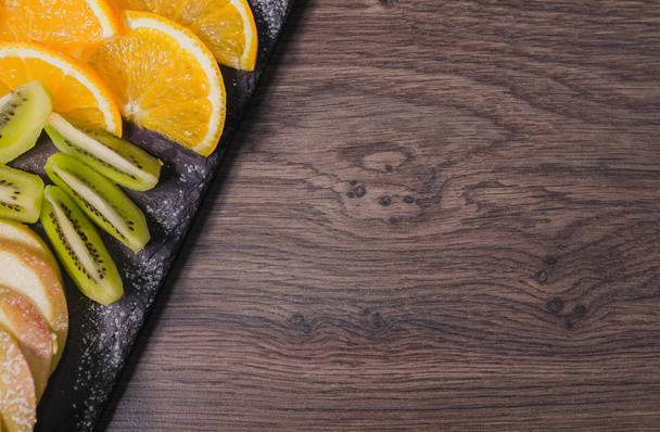 Corte de fruta sobre un fondo de madera y sobre un soporte de piedra
 - Foto, Imagen