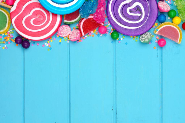 Borde superior de caramelos coloridos surtidos sobre un fondo de madera azul
 - Foto, imagen