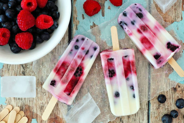 Group of homemade mixed berry yogurt popsicles on a rustic wood background - Фото, зображення