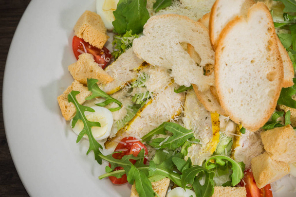 Cézár saláta egy fehér tányérra egy fából készült háttér - Fotó, kép