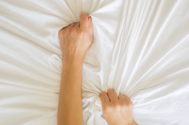 Hand sign orgasm of woman on white bed , Hand of female pulling white sheets in ecstasy , feeling and emotion concept - Foto, Imagem