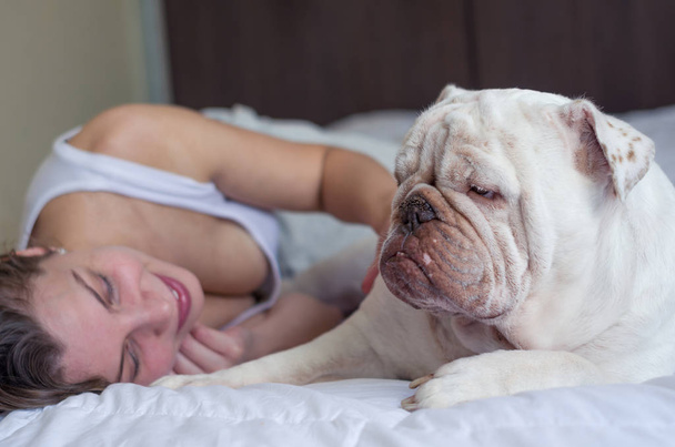 Beautiful woman sleeping in bed with english bulldog puppy. - Фото, зображення