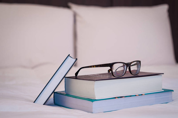 Books on the white bed, glasses on top. - Foto, Imagem