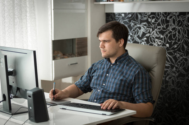 Retrato de un joven diseñador gráfico masculino que trabaja en casa con una tableta gráfica
 - Foto, imagen