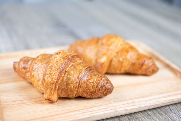 Two croissant are placed on a wooden chopping board , select focas shallow depth of field - Photo, Image