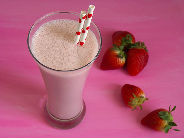 Delicious strawberry smoothie, with strawberries isolated on a pink background - Photo, Image