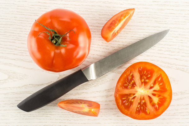 Composition tomate rouge avec un couteau isolé sur fond de bois gris vue du dessus une demi-section entière et deux tranches
 - Photo, image