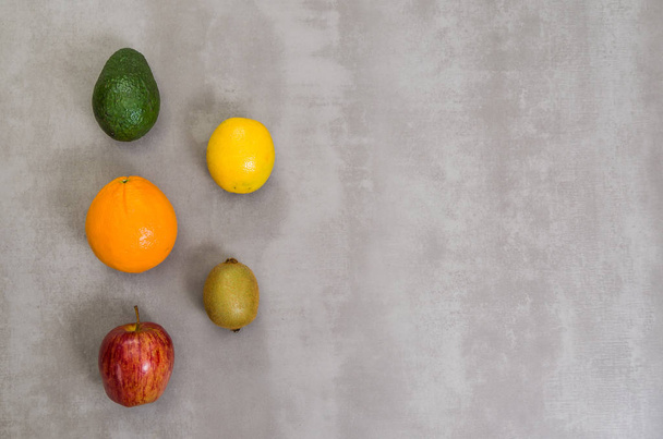Great concept of healthy eating, various fruits on gray background, polished concrete. Orange, apple, kiwi, lemon. - Foto, Imagen
