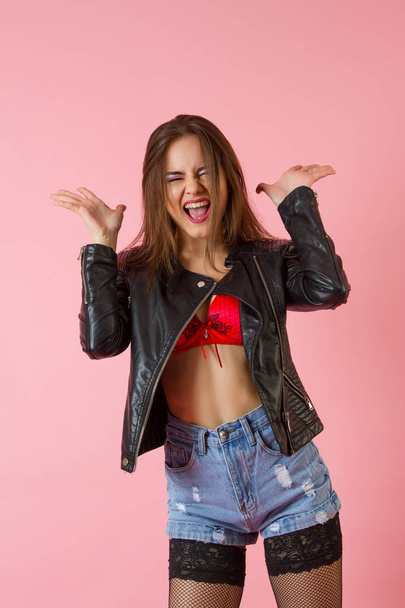 Young emotional girl in a leather jacket and denim shorts - Foto, imagen