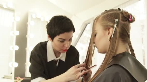 Mujer estilista usando maquinilla de afeitar para cortar el pelo largo en el estudio de belleza. Primer plano peinado femenino en el salón de peluquería
. - Imágenes, Vídeo