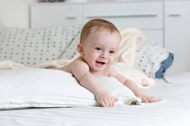 Portret urocza 9 miesięcy życia chłopca leżącego na dużą poduszkę na łóżku - Zdjęcie, obraz
